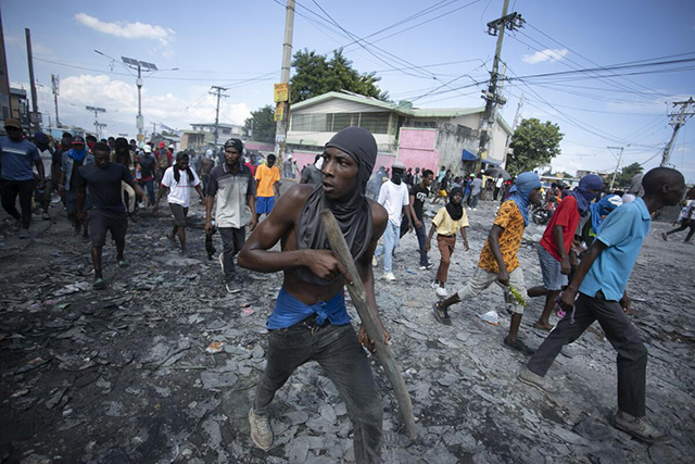 Un manifestante porta un pedazo de madera que finge es un rifle durante una protesta antigubernamental en Puerto Prncipe el 3 de octubre del 2022. (Odelyn Joseph / Associated Press)